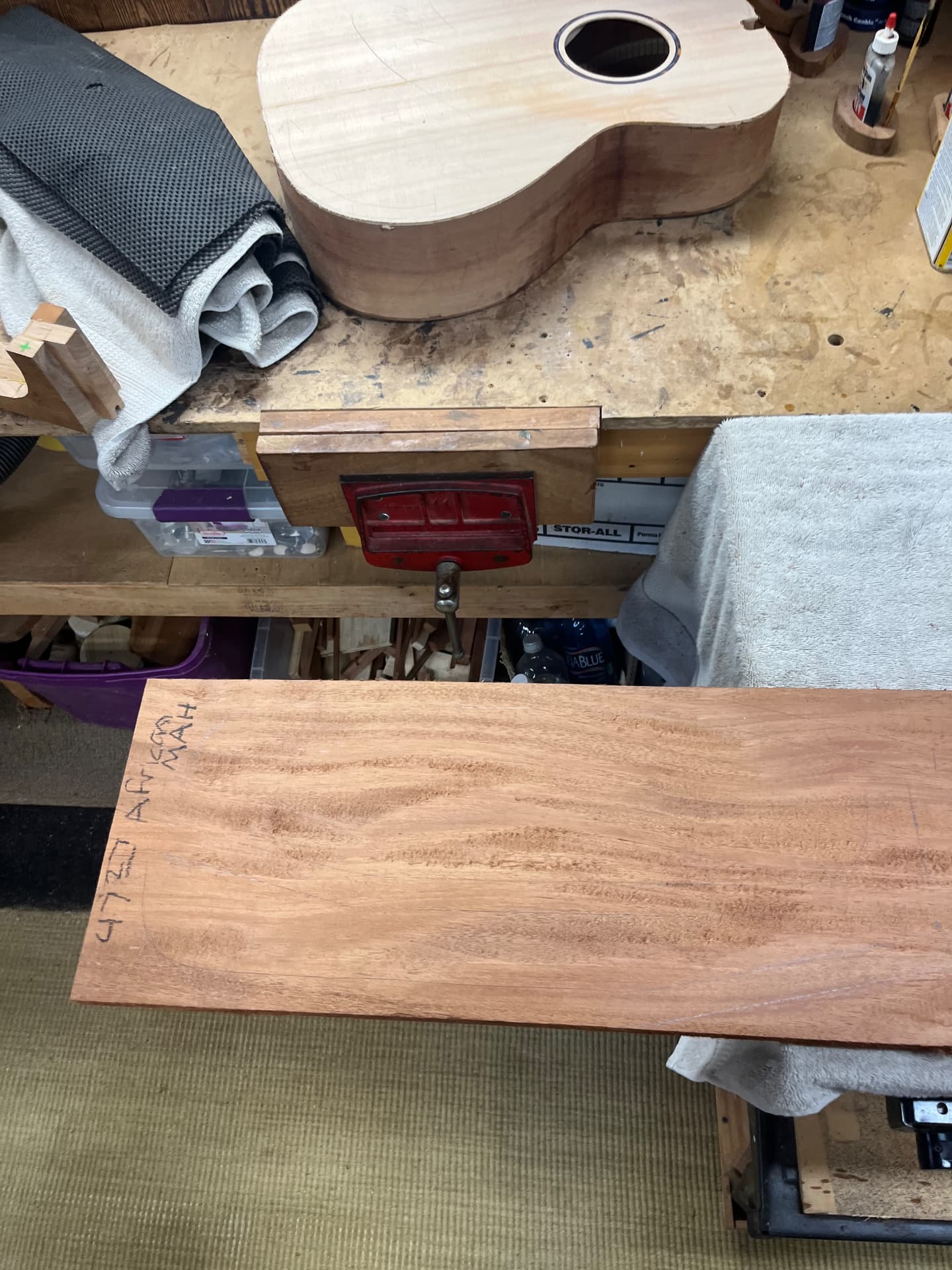 Sapele neck board on the workbench beside the assembled guitar body
