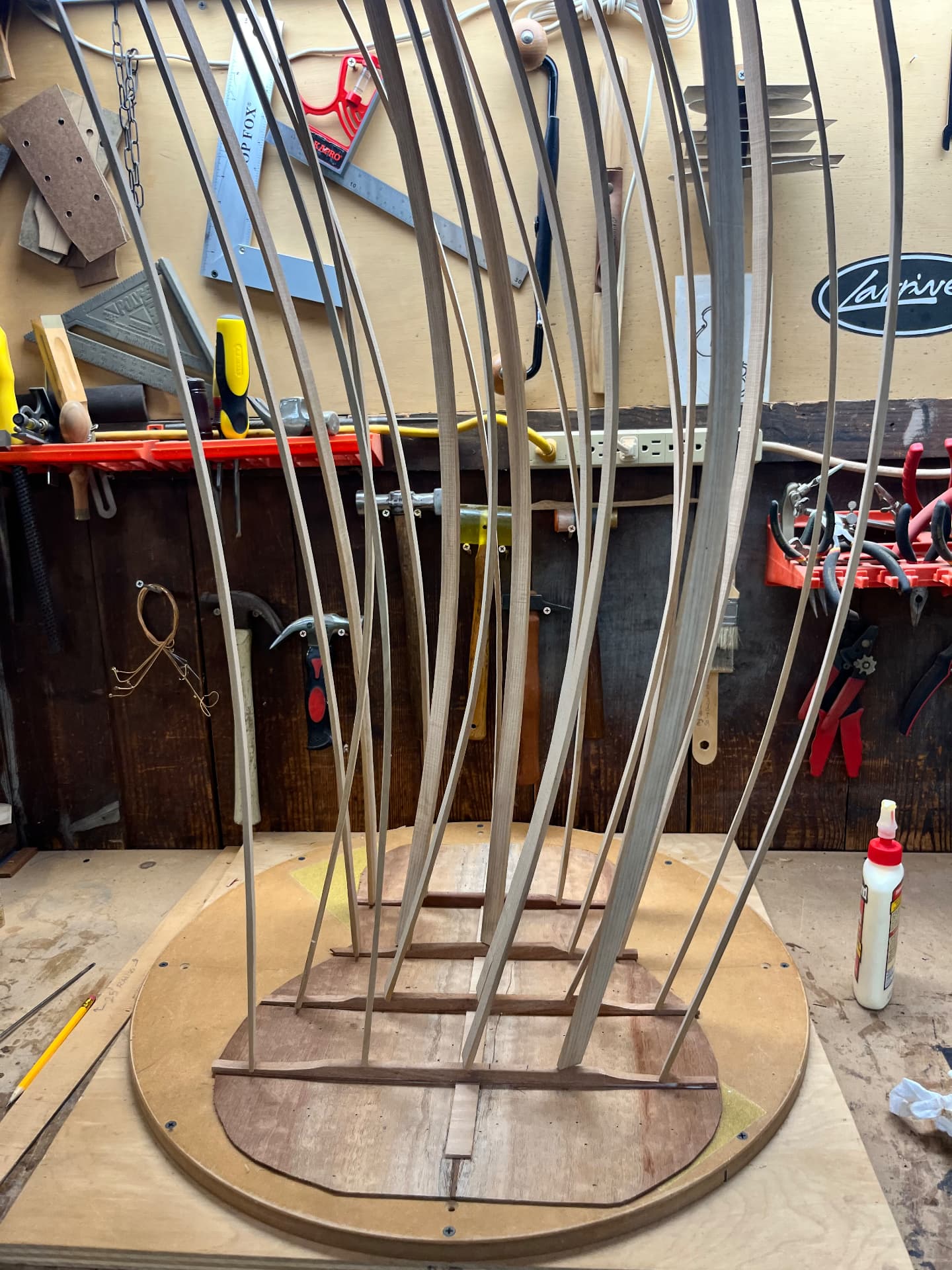 Spruce brace stock clamped upright over the guitar back in the workshop