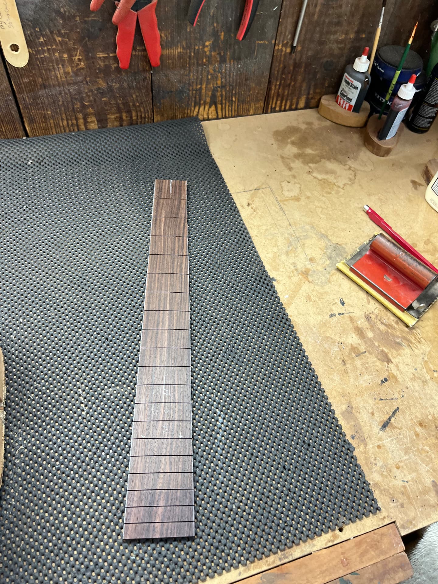 Rosewood fingerboard with fret slots cut, resting on a workshop mat