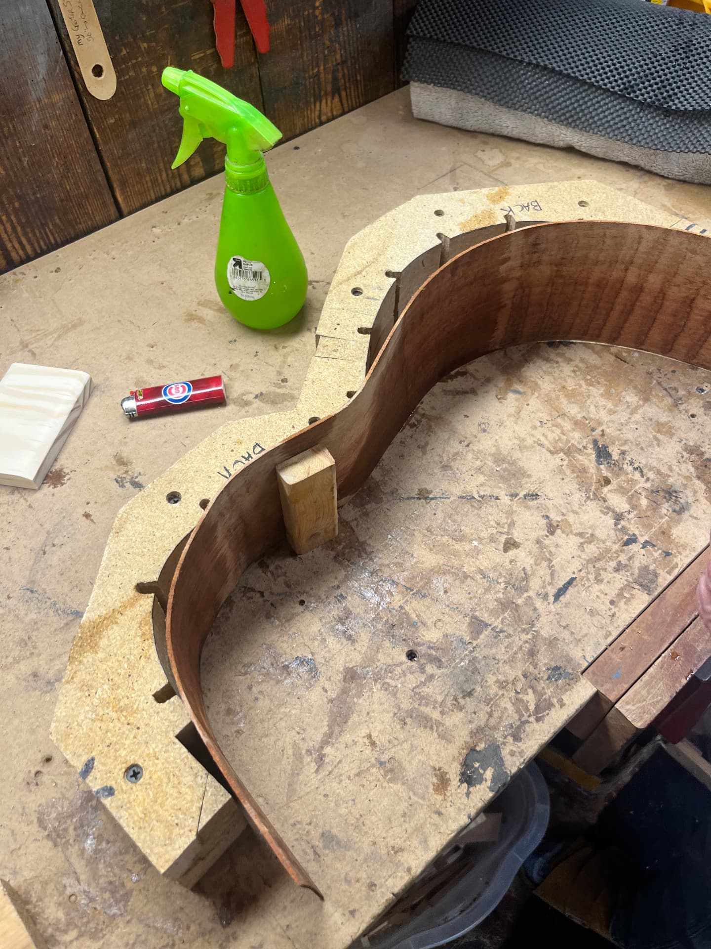 Bent sapele side standing in the body mold on the workbench