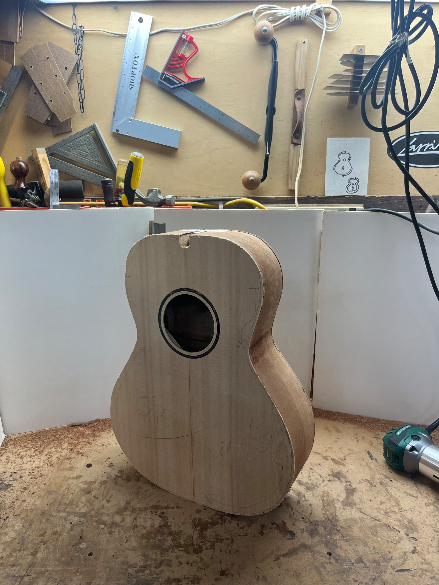 Assembled guitar body standing on the workbench with pencil marks around the edges