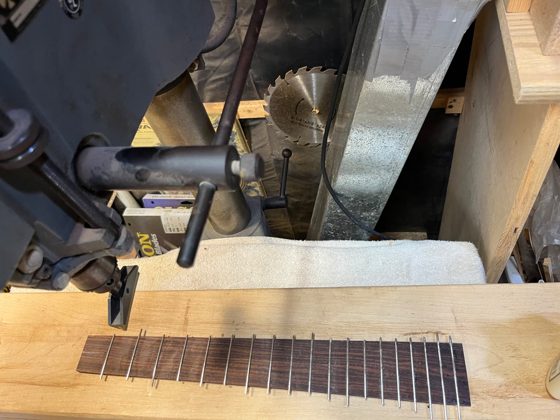 Rosewood fingerboard with frets installed, clamped near the saw